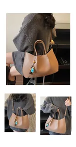 Detail einer braunen Shopper-Tasche aus Leder mit Litschi-Muster und buntem Perlenanhänger