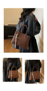 Détail du sac cabas en cuir marron avec accessoire de chaîne et logo de mode gravé