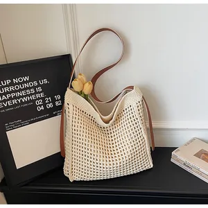 Gros plan d'un sac cabas tissé crème avec bandoulières en cuir marron et tulipes jaunes