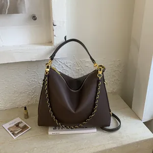 Dark brown pebble leather Hobo bag with gold chain strap on a stone display stand