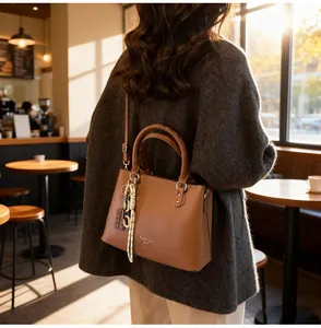 Détail d'un sac cabas en cuir marron avec logo embossé et pendentif chocolat décoratif