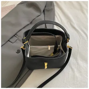 Minimalist black faux leather bucket bag with gold hardware and interior zip compartment