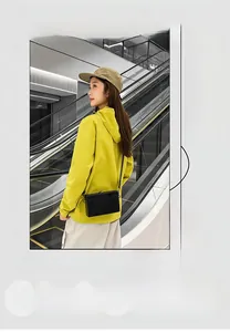 Detailed view of a sleek black box crossbody bag styled with a vibrant yellow hoodie
