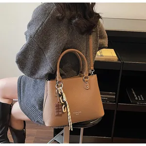 Détails du sac marron en cuir grainé avec texte Fashion Bag et pendentif décoratif