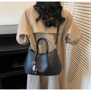 Modell mit schwarzer Tote-Bag aus Lychee-Leder mit Ethno-Perlenanhänger und Schultergurt