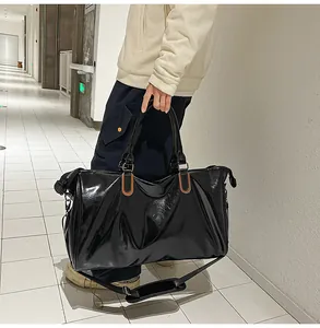 Detail of high-gloss black travel bag with brown accents and polished finish texture