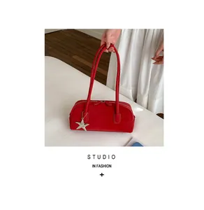 Detail of red suede baguette bag featuring silver star pendant and twin metal zippers
