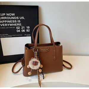 Detail of brown litchi pattern leather bag with detachable strap and bear charm