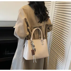 Détail d'un sac cabas beige avec texture grainée et accessoire foulard élégant