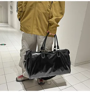 Detail view of large black faux leather travel bag with glossy finish and metal buckles