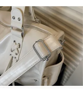 Detail of adjustable long shoulder strap and silver metal hardware on cream PU tote bag