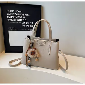 Beige lychee pattern crossbody tote bag with dual handles and plush bear charm