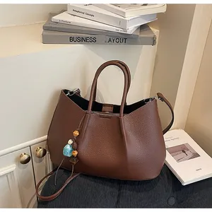 Detail der dunkelbraunen Leder-Tote-Bag mit weicher Lychee-Struktur und Perlenanhänger