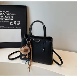 Detail of black lychee grain leather tote bag with silver plate and cute plush charm