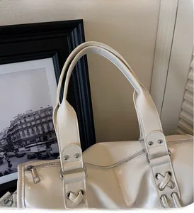 Close-up of white tote bag with silver rivets, criss-cross lacing and metallic zipper
