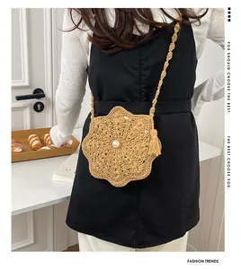 Detail of hand-crocheted floral crossbody bag featuring a central pearl and woven strap