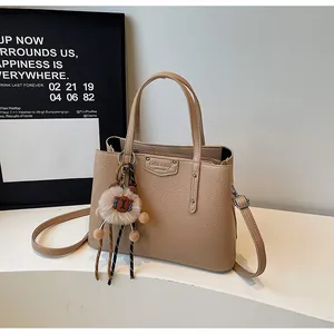Detail of lychee textured camel leather bag with silver buckle and plush bear charm