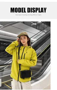 Modern black box crossbody bag styled with a vibrant yellow outdoor jacket and casual pants
