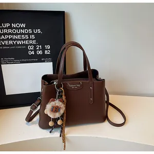 Detail of dark brown lychee textured bag with silver logo tag and plush bear charm