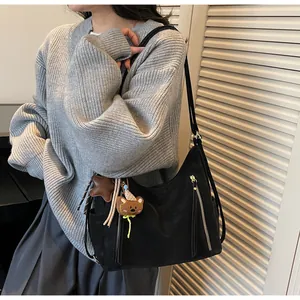 Détail du sac cabas en toile noire avec fermetures éclair et pendentif ours mignon