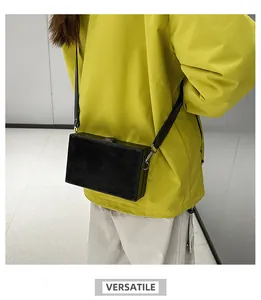 Detail of a black box-shaped crossbody bag made of matte PU leather on a fashion model