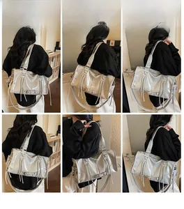 Detail view of glossy silver tote bag featuring metallic hardware and long fringe accents