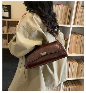 Dettaglio della borsa a spalla in pelle lucida marrone scuro con fibbia dorata