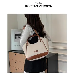 Détail d'un sac cabas bicolore minimaliste en crème et marron avec plaque métallique