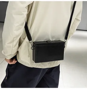 Detail of black box-shaped crossbody bag with textured PU leather and metal buckle