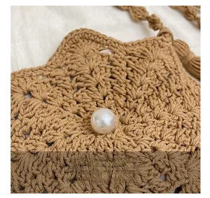 Close-up of handmade hollow crochet knit bag featuring brown yarn and a pearl button