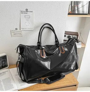 Detail of waterproof black faux leather duffel bag with silver hardware and shoulder strap
