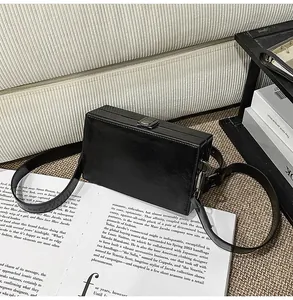 Detail of minimalist black box bag featuring glossy PU leather and silver metal push lock