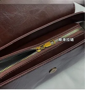 Dettaglio della zip dorata e pelle martellata marrone scuro della borsa baguette