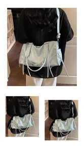 Detail of light blue glossy PU tote bag featuring decorative long ribbons and buckles