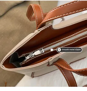Gros plan de la fermeture éclair argentée et des coutures sur le sac fourre-tout crème