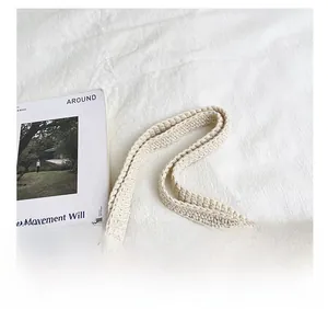 Close-up of thick crochet knit strap on a two-tone straw tote bag with magazine