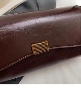 Dettaglio della borsa a tracolla vintage in pelle cerata marrone con fibbia dorata