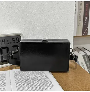 Close-up of a black box shoulder bag with silver hardware on a wooden table setup