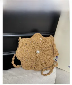 Detail of khaki star-shaped hand-woven bag with pearl accent and tassel on sofa