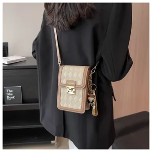 Detail of beige and brown quilted crossbody bag with gold buckle and fashion label