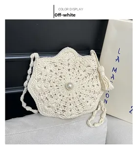 Detail of hand-woven cream shoulder bag with large pearl accent and elegant side tassel