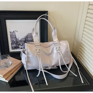 Detail of lavender glossy tote bag featuring metal eyelets and long fringe tassels