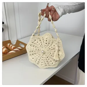 Close-up of handmade crochet straw bag with flower pattern and pearl tassel detail