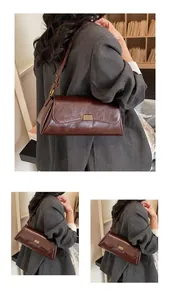 Dettaglio della borsa a spalla in pelle marrone scuro con fibbia dorata e texture
