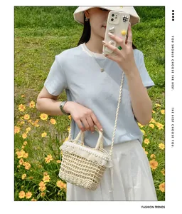 Close-up of beige woven bucket bag with delicate lace trim and pearl accents