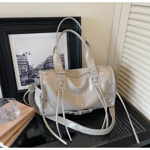 Detailed macro view of cream PU leather handbag with fringe tassel and metallic rivets