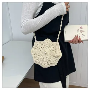 Close-up of white handmade crochet shoulder bag featuring pearl buckle and tassel details