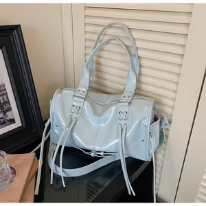 Detail of light blue glossy tote bag with stylish fringe tassels and crisscross straps