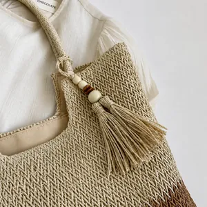 Detail view of woven straw beach bag featuring wooden beads and decorative tassel