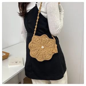 Detail of straw woven flower crossbody bag with pearl center and tassel accent